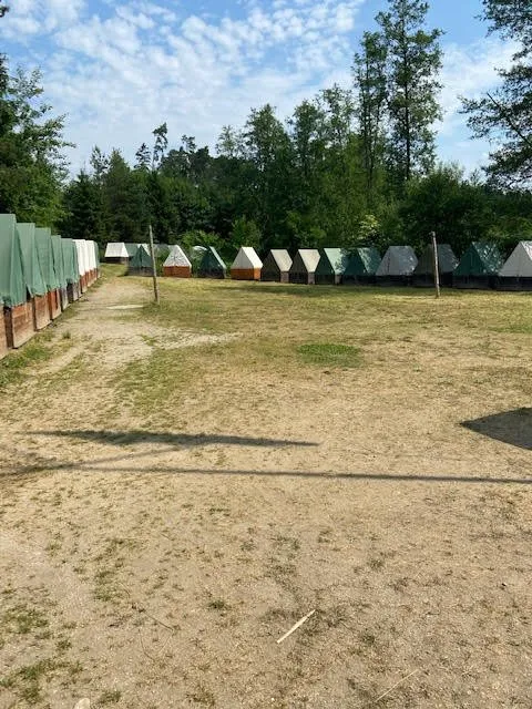 Řada stanů kolem táborové louky.
